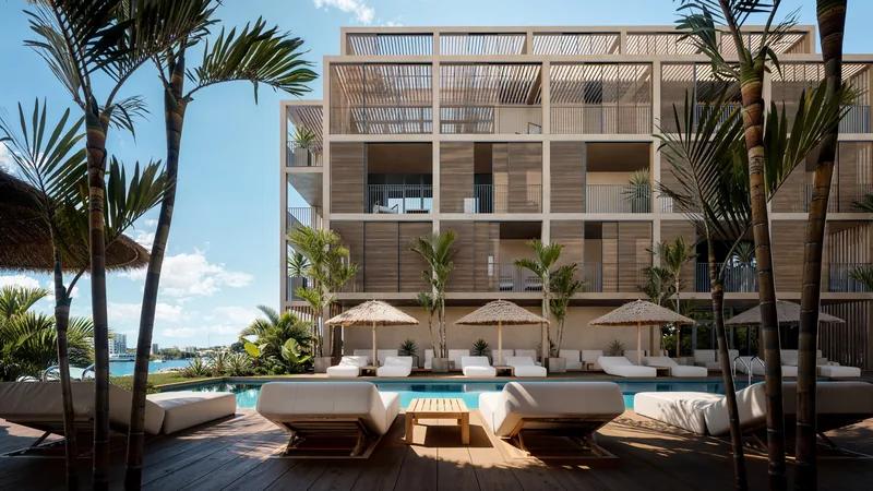 an apartment building above a pool lined with day beds and parasols under palms