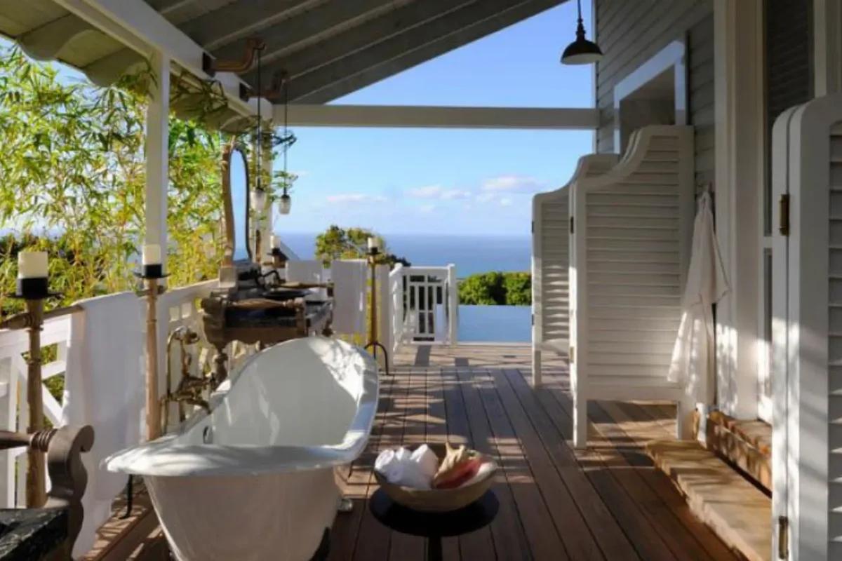 A roll-top bath on a timber verandah deck, open to the sea view