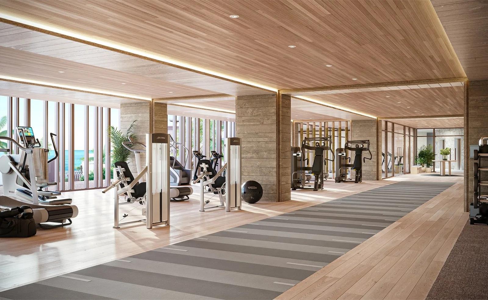 A long fitness room with rows of cardio machines under a timber ceiling